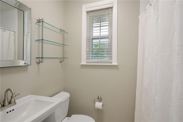 bathroom featuring a sink, toilet, and curtained shower