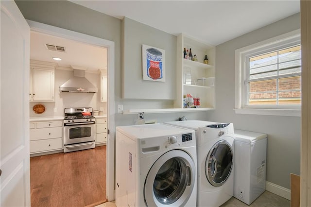 laundry area with washer and dryer, light wood-style flooring, and baseboards