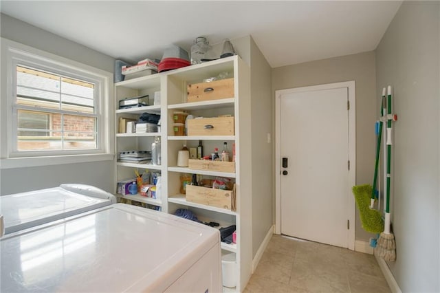 washroom with washing machine and dryer, baseboards, and light tile patterned floors