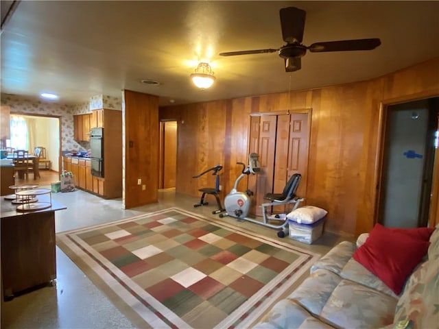 workout room featuring wooden walls and ceiling fan