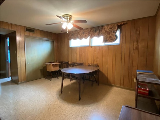 dining space featuring wooden walls, visible vents, and ceiling fan