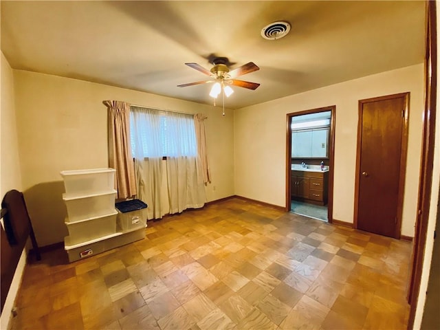 unfurnished bedroom featuring ensuite bathroom, visible vents, ceiling fan, and baseboards