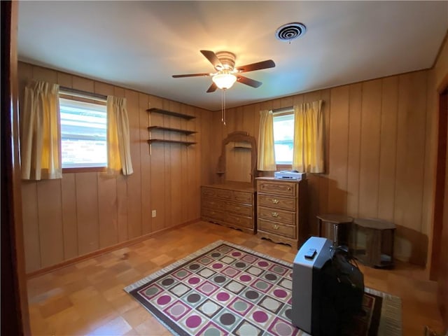 bedroom with wooden walls, visible vents, baseboards, and light floors