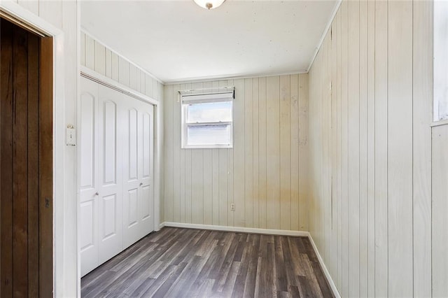 1017 Elmeer Ave, Metairie, LA 70005 - unfurnished bedroom featuring a closet, dark wood-style flooring, baseboards, and wood walls
