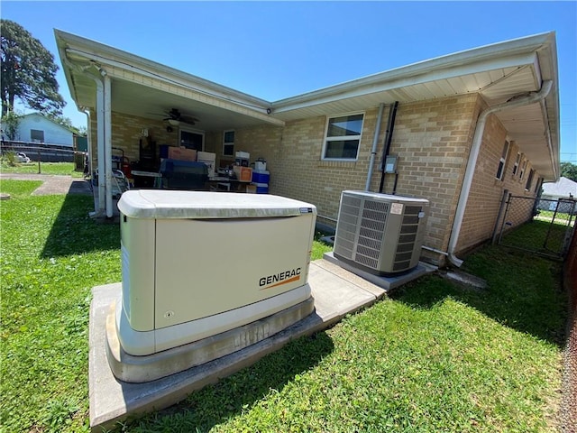 details featuring cooling unit, a power unit, fence, a ceiling fan, and brick siding