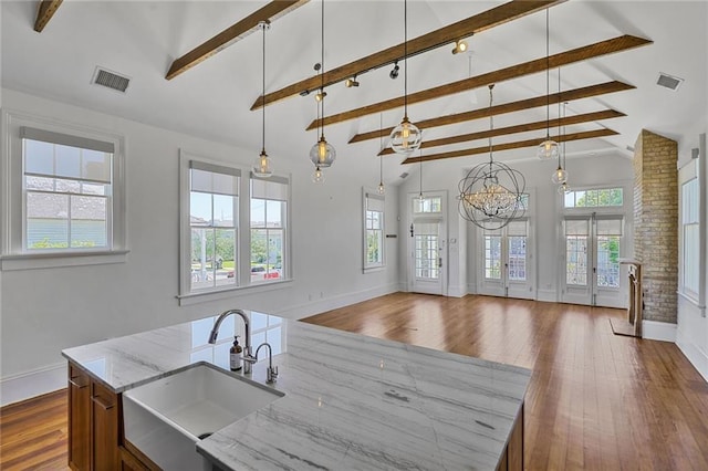 kitchen with a sink, beam ceiling, and plenty of natural light