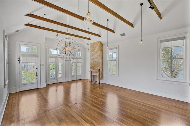 unfurnished living room with a wealth of natural light, visible vents, and hardwood / wood-style flooring