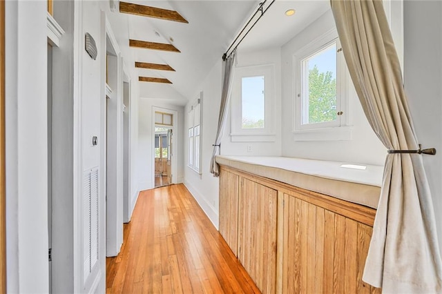 hall featuring baseboards, light wood-type flooring, and lofted ceiling with beams