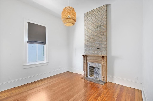 unfurnished living room with a fireplace, baseboards, and wood finished floors
