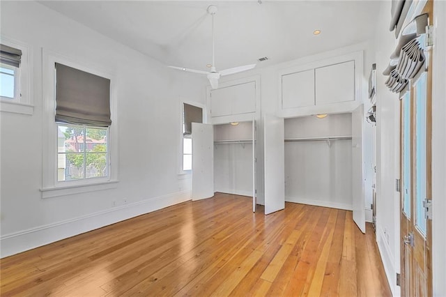 unfurnished bedroom featuring multiple windows, light wood finished floors, two closets, and visible vents