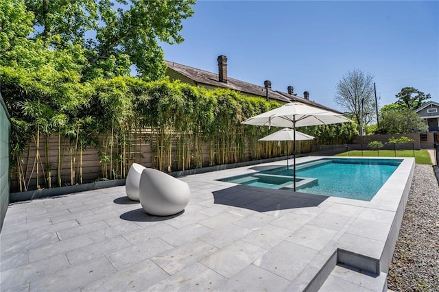 view of pool featuring a patio area, a fenced backyard, and a pool with connected hot tub