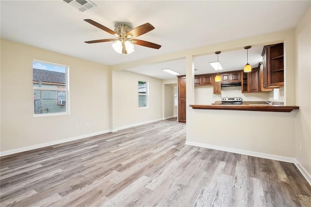 kitchen featuring light wood-type flooring, electric range, open shelves, under cabinet range hood, and visible vents