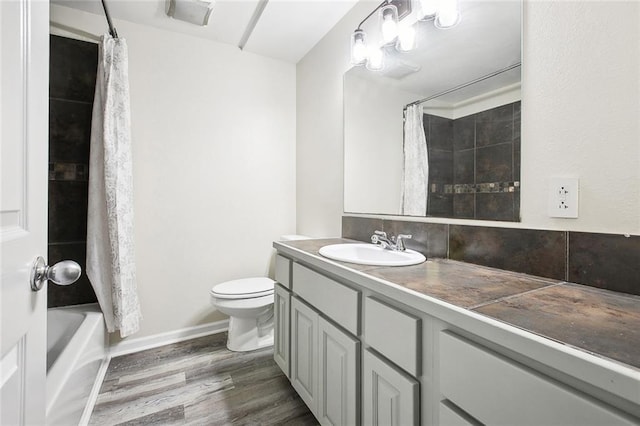 bathroom with vanity, baseboards, shower / bath combination with curtain, toilet, and wood finished floors