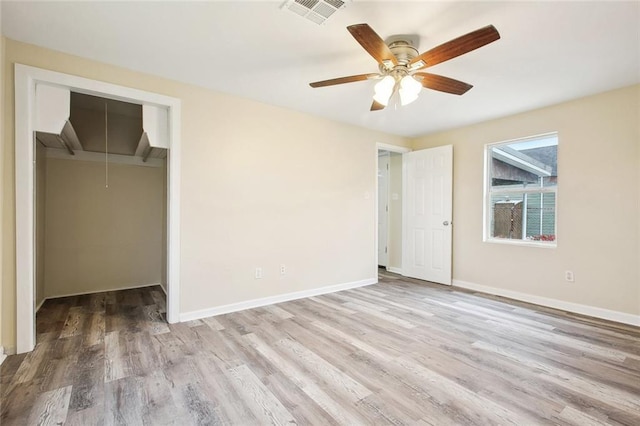 unfurnished bedroom with a closet, visible vents, wood finished floors, attic access, and baseboards
