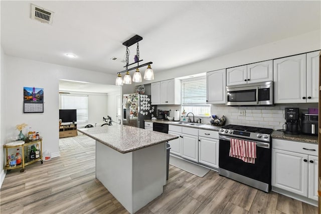 5387 Chamberlain Dr, New Orleans, LA 70122 - kitchen featuring tasteful backsplash, light wood-type flooring, visible vents, stainless steel appliances, and a sink