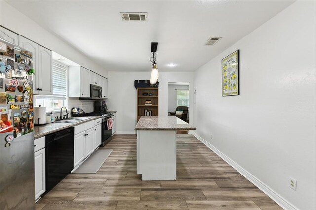 5387 Chamberlain Dr, New Orleans, LA 70122 - kitchen with white cabinets, visible vents, black appliances, a center island, and a sink