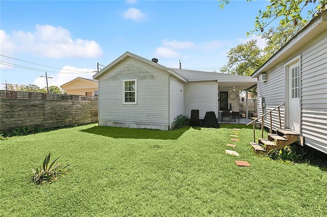 rear view of property featuring fence, a lawn, entry steps, and a patio