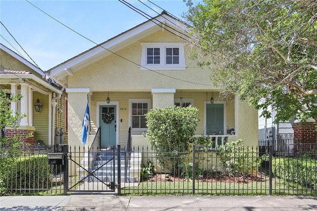 view of front of property featuring a gate, stucco siding, covered porch, and a fenced front yard