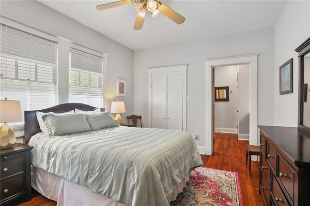 bedroom featuring ceiling fan, a closet, dark wood-style flooring, and baseboards