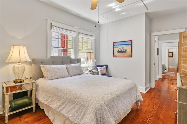 bedroom with baseboards, attic access, ceiling fan, and wood finished floors