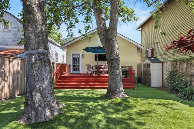 rear view of house with a wooden deck, a yard, an outdoor structure, a storage unit, and fence
