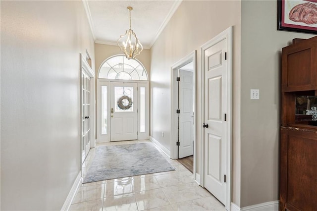 foyer entrance with crown molding, marble finish floor, baseboards, and a notable chandelier