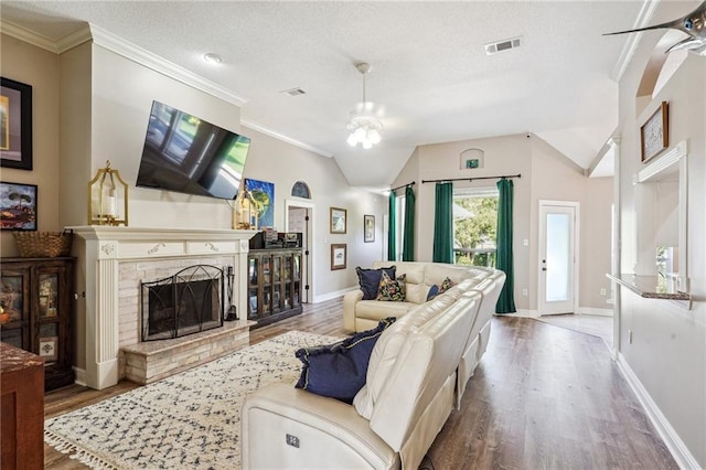 living area featuring a fireplace, vaulted ceiling, wood finished floors, and visible vents