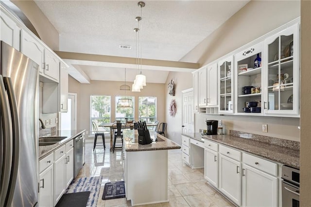 kitchen featuring a kitchen island, visible vents, a sink, glass insert cabinets, and stainless steel appliances