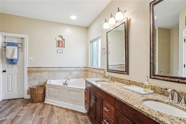 full bathroom featuring a garden tub, a sink, wood finished floors, and a wainscoted wall