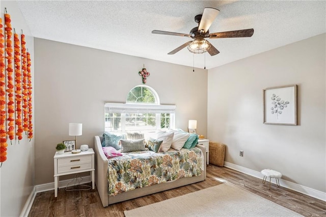 bedroom with baseboards, ceiling fan, a textured ceiling, and wood finished floors