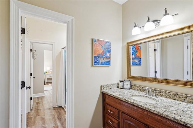 full bathroom featuring vanity, baseboards, and wood finished floors