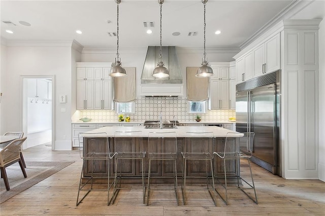 316 Sena Dr, Metairie, LA 70005 - kitchen with visible vents, ornamental molding, built in refrigerator, a spacious island, and custom exhaust hood