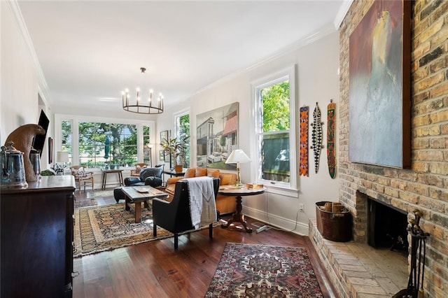 living area featuring baseboards, crown molding, dark wood-style flooring, a brick fireplace, and a notable chandelier
