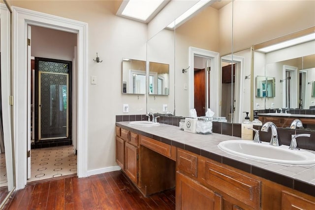 full bathroom with baseboards, hardwood / wood-style floors, double vanity, and a sink