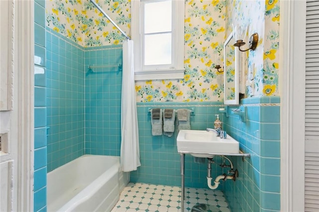 bathroom featuring a sink, wallpapered walls, tile walls, tile patterned flooring, and wainscoting