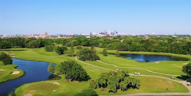 view of urban area featuring a nearby body of water, a golf course, and a tree filled landscape