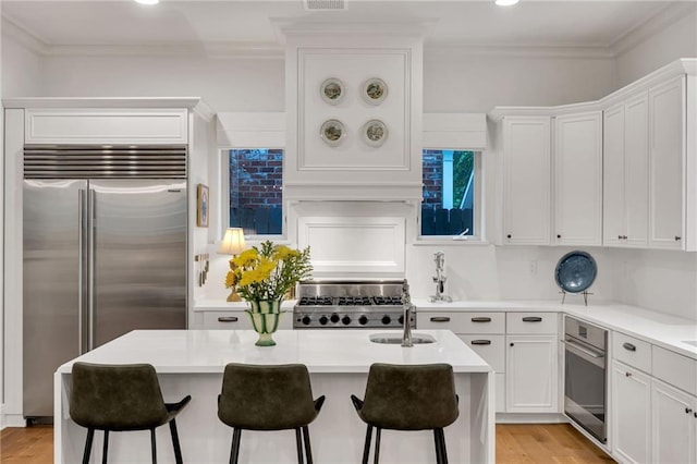 225 Ridgewood Dr, Metairie, LA 70005 - kitchen with white cabinetry, a breakfast bar, light countertops, stainless steel appliances, and a center island with sink