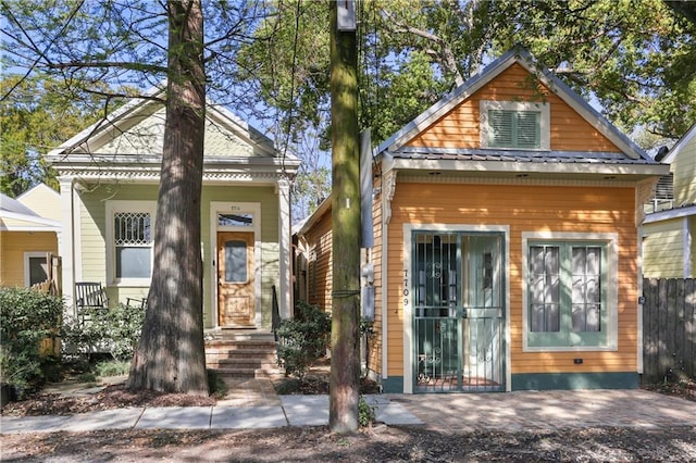 shotgun-style home with metal roof and fence