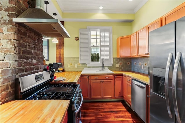 kitchen with butcher block countertops, crown molding, appliances with stainless steel finishes, and extractor fan