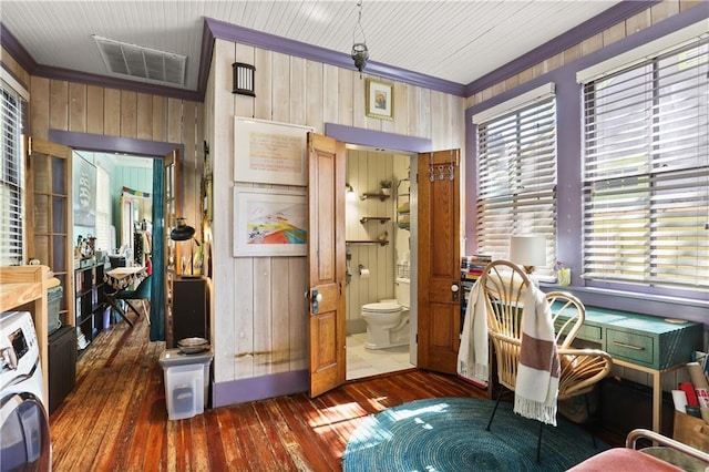 interior space with crown molding, wood walls, washer / dryer, visible vents, and hardwood / wood-style flooring