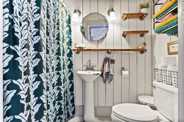bathroom with toilet, curtained shower, and a sink