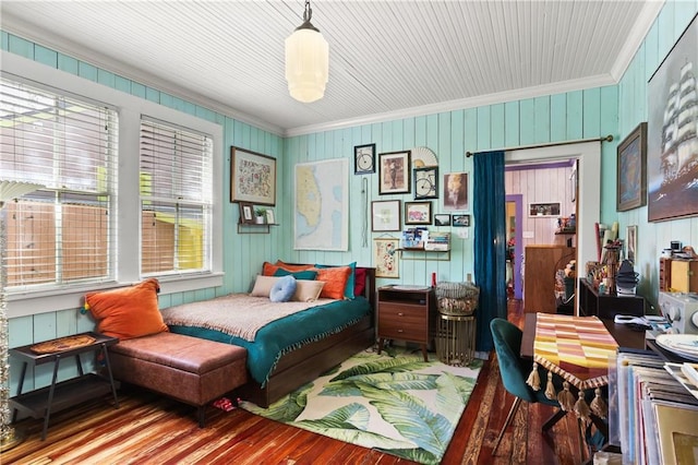 bedroom featuring wooden walls, ornamental molding, and wood finished floors