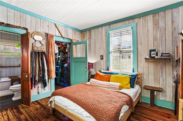bedroom with crown molding, a closet, wooden walls, and wood finished floors