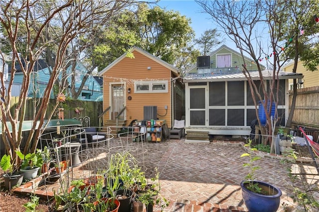 rear view of property with a sunroom, entry steps, a patio area, metal roof, and fence