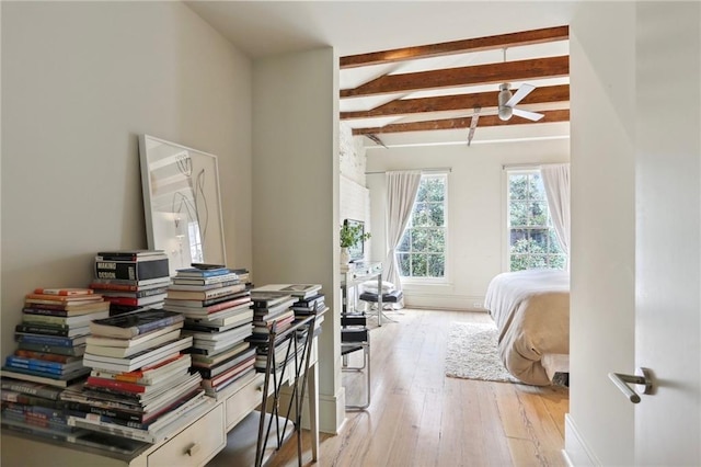 bedroom featuring light wood-style flooring, baseboards, and beam ceiling