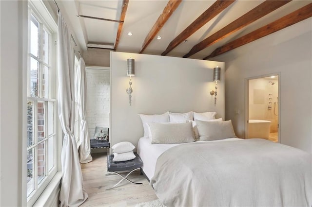 bedroom featuring beamed ceiling, ensuite bath, and wood finished floors