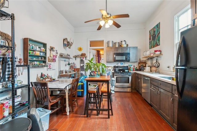 kitchen with light countertops, dark brown cabinets, dark wood-type flooring, ceiling fan, and black appliances