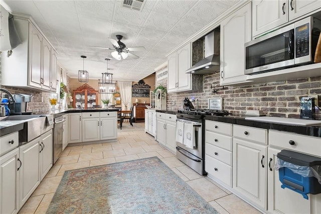 313 Sarah Victoria Dr, Belle Chasse, LA 70037 - kitchen featuring a peninsula, a ceiling fan, visible vents, wall chimney exhaust hood, and stainless steel appliances