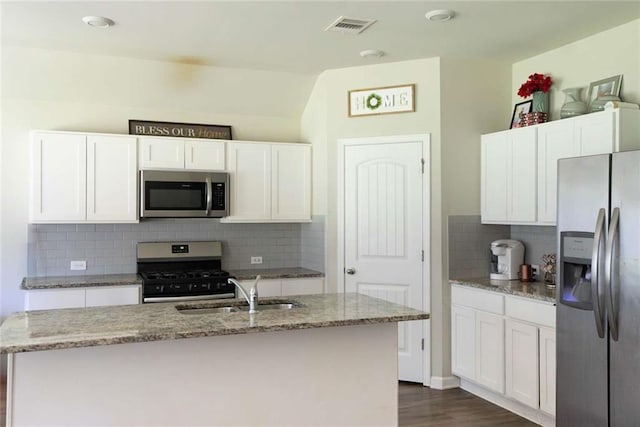kitchen featuring visible vents, a sink, appliances with stainless steel finishes, decorative backsplash, and light stone counters