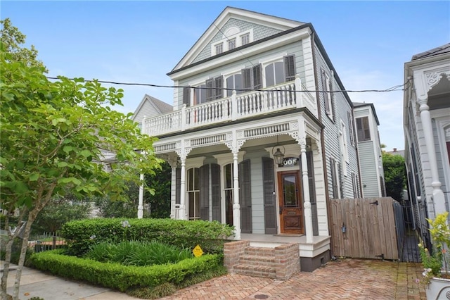view of front of house featuring a balcony, covered porch, and fence